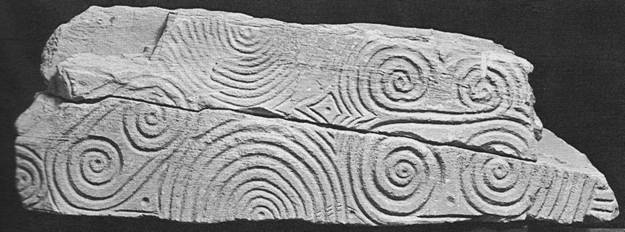 A black and white photograph showing a large stone decorated with spirals